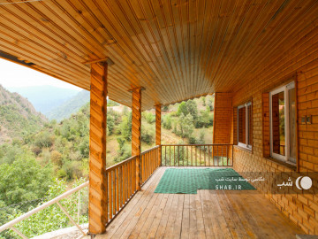 تصویر اقامتگاه چوبی با چشم انداز جنگل و کوه